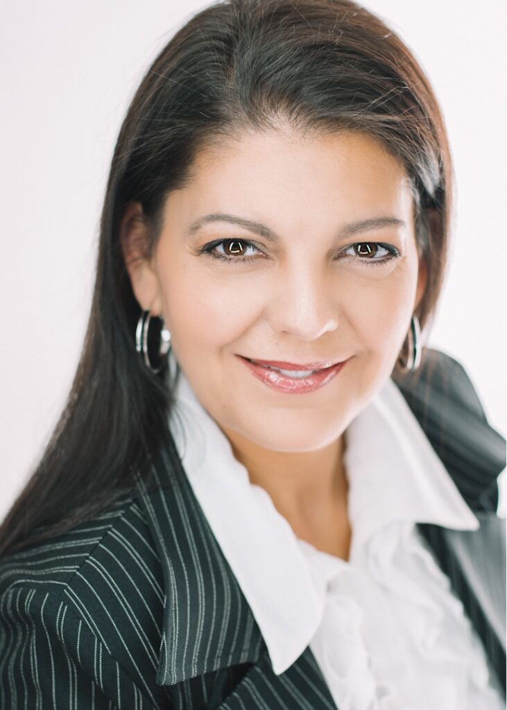 A woman with long hair wearing a suit and white shirt.