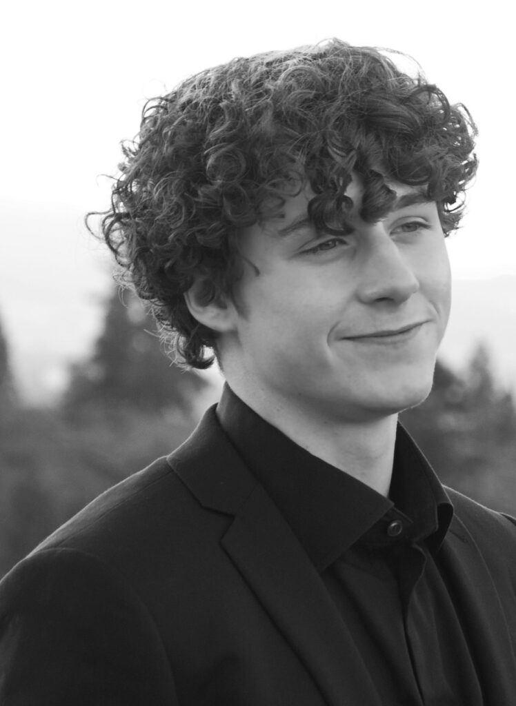 A man with curly hair wearing a suit and tie.