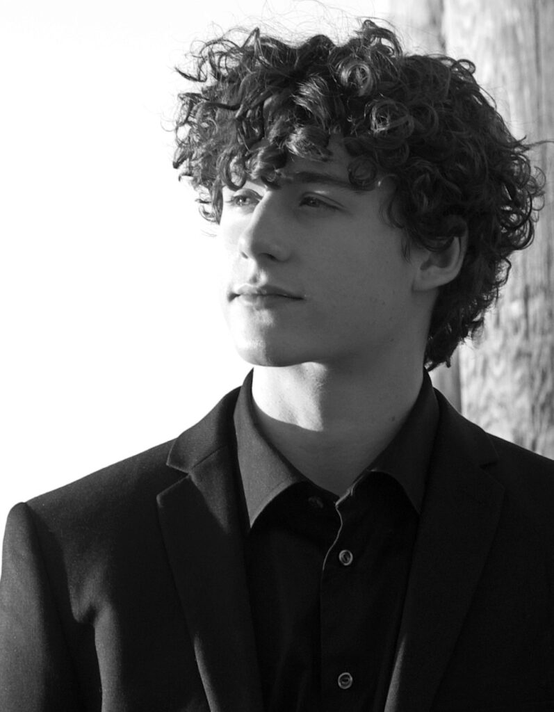 A man with curly hair wearing a suit and tie.