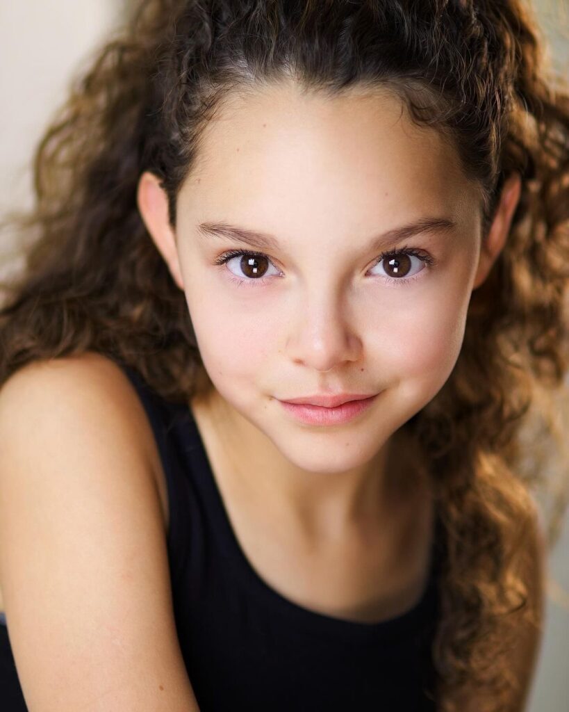 A young girl with long curly hair and pink eyes.