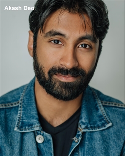 A man with beard and blue jacket smiling for the camera.